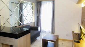 A modern living room with a sofa, a coffee table, and a TV. - Modern and Clean 2BR Apartment at M-Town Residence (Gading Serpong)