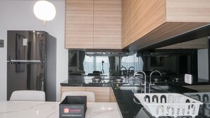 A modern kitchen with a stainless steel refrigerator, wooden cabinets, a black countertop, and a white island with a basket.