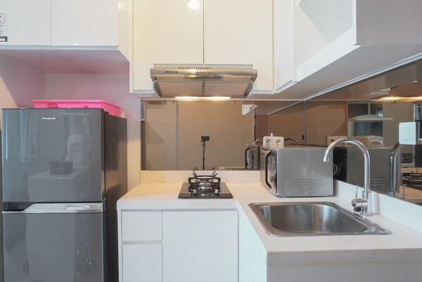A modern kitchen with a built-in gas stove, a stainless steel sink, and a compact refrigerator.
