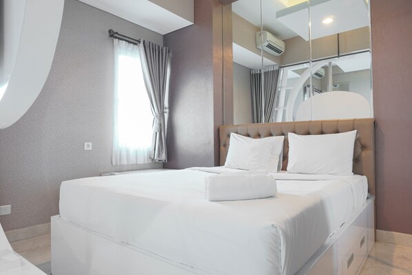 A modern hotel room with a large bed, a mirror, and a view of the staircase. - Premium and Spacious Studio Apartment at Capitol Park Residence (Jakarta)