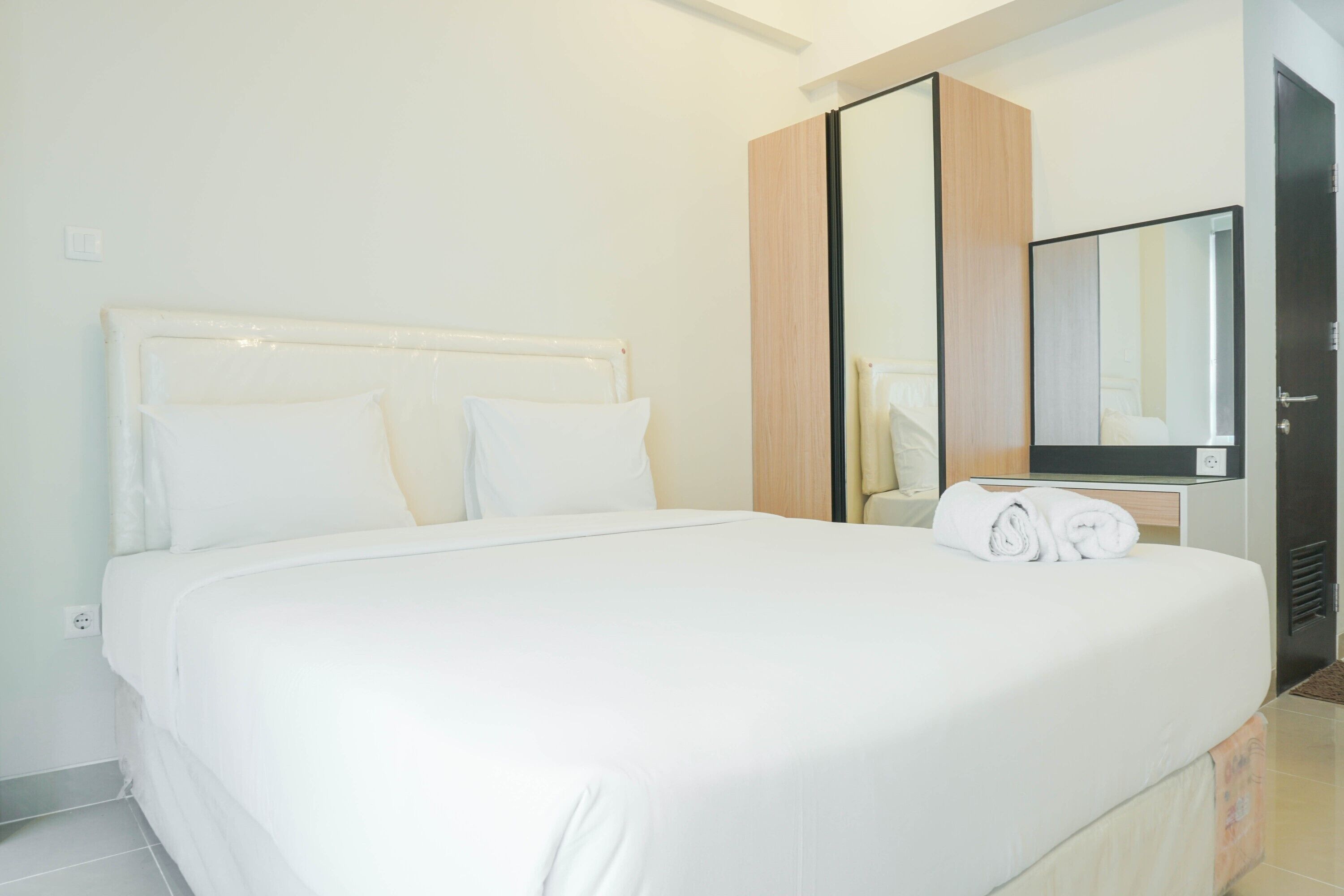 Un lit bien fait, avec du linge de lit blanc, dans une chambre d'hôtel.