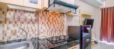 Una cocina con estufa a gas, lavamanos y refrigerador.