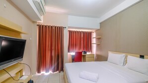 Une chambre d’hôtel équipée d’un lit, d’un bureau avec une chaise, d’une télévision et d’un appareil de climatisation.