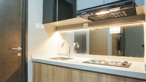 A modern kitchen with a stainless steel sink, a built-in range hood, and wooden cabinets. - Elegant 1BR Apartment with Working Space Mustika Golf Residence (Cikarang)