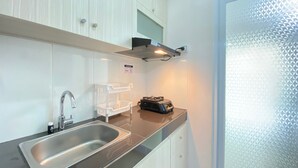 Una cocina moderna con un lavamanos de acero inoxidable, armarios blancos y encimera negra.