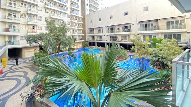 Un edificio residencial con varios balcones, piscina y abundante vegetación.