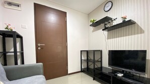 Una sala de estar con una puerta marrón, un mueble negro para televisión y un sofá.