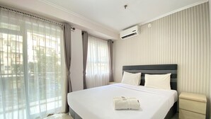 Una habitación de hotel con una cama grande, una mesita de noche y un ventanal con cortinas.