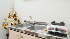 Una cocina con un lavamanos doble, una estufa a gas y un arreglo floral decorativo.