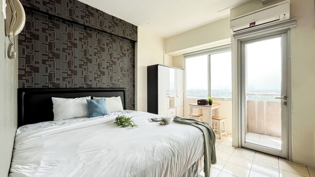 Un dormitorio moderno con una cama grande, vistas a la ciudad desde un balcón y un armario.
