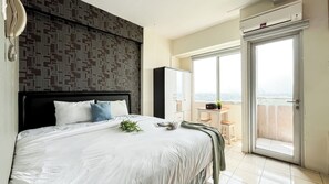 Ein modernes Schlafzimmer mit einem großen Bett, Blick auf die Stadt durch einen Balkon und einem Kleiderschrank.