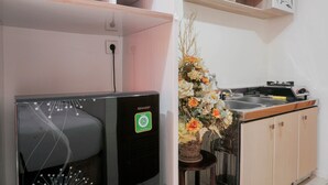 Una cocina compacta con un refrigerador empotrado, un lavamanos y una estufa. Hay un florero con flores sobre la encimera.