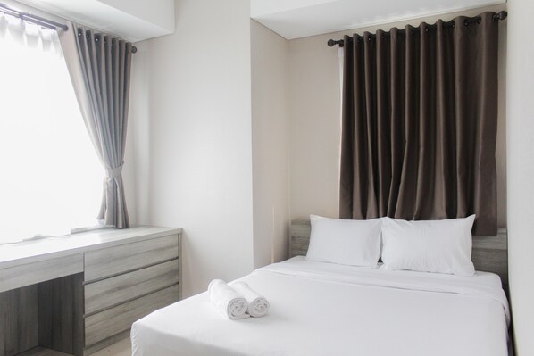 Una habitación de hotel con cama, escritorio y ventana con cortinas.
