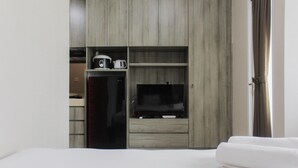 Ein Hotelzimmer mit einem Bett, einem Fernseher, einer Minibar und einem Holzschrank.