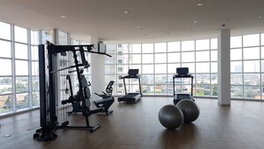 A spacious gym with large windows, exercise equipment, and a city view.