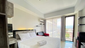 Een moderne hotelkamer met een groot bed, een rode stoel, een televisie en een balkon met uitzicht.