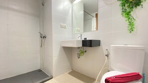 Een badkamer met douche, toilet, wastafel en een spiegel.