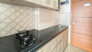 Een keuken met een zwart fornuis, een spoelbak en houten kastjes.