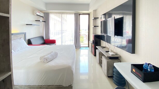 Een hotelkamer met een bed, een bureau, een televisie en een raam met gordijnen.