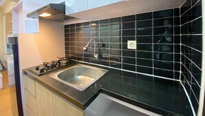 Eine moderne Küche mit schwarzer Fliesenrückwand, Spüle aus Edelstahl und Holzschränken.