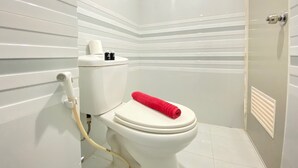 Ein modernes Badezimmer mit einer weißen Toilette, einem roten Handtuch auf dem Sitz und einer Duschkabine.