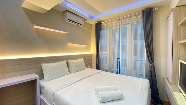 Ein modernes Hotelzimmer mit einem ordentlich bezogenen Bett, einer Klimaanlage, einem Nachttisch und einem großen Fenster mit Vorhängen.