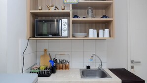 A kitchen with a microwave, sink, and various utensils. - Modern 2BR Apartment @ Springlake Summarecon (Bekasi)