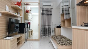 A compact hotel room with a bed, a TV, a refrigerator, and a small kitchen area. - Modern 2BR Apartment @ Springlake Summarecon (Bekasi)