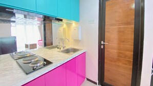 A kitchen with a stainless steel sink, a built-in stove, and teal cabinets. - Modern & Cozy 2BR at Gateway Pasteur Apartment (Cimahi)