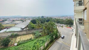 A residential area with a view of a cityscape, a parking lot, and a building with balconies. - Modern & Cozy 2BR at Gateway Pasteur Apartment (Cimahi)