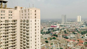 A high-rise building with multiple floors and balconies, surrounded by a densely populated urban area with various buildings and infrastructure. - Simply Studio Room Apartment Margonda Residences 5 (Depok)