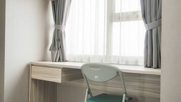 Un escritorio con una silla, una ventana con cortinas y una pared de color claro.