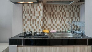 A modern kitchen with a black countertop, a stainless steel sink, and a tiled backsplash. - Simply Studio Room Apartment Margonda Residences 5 (Depok)