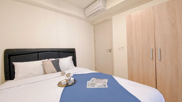 Hotellihuone, jossa on sänky, puinen vaatekaappi ja ilmastointilaite.