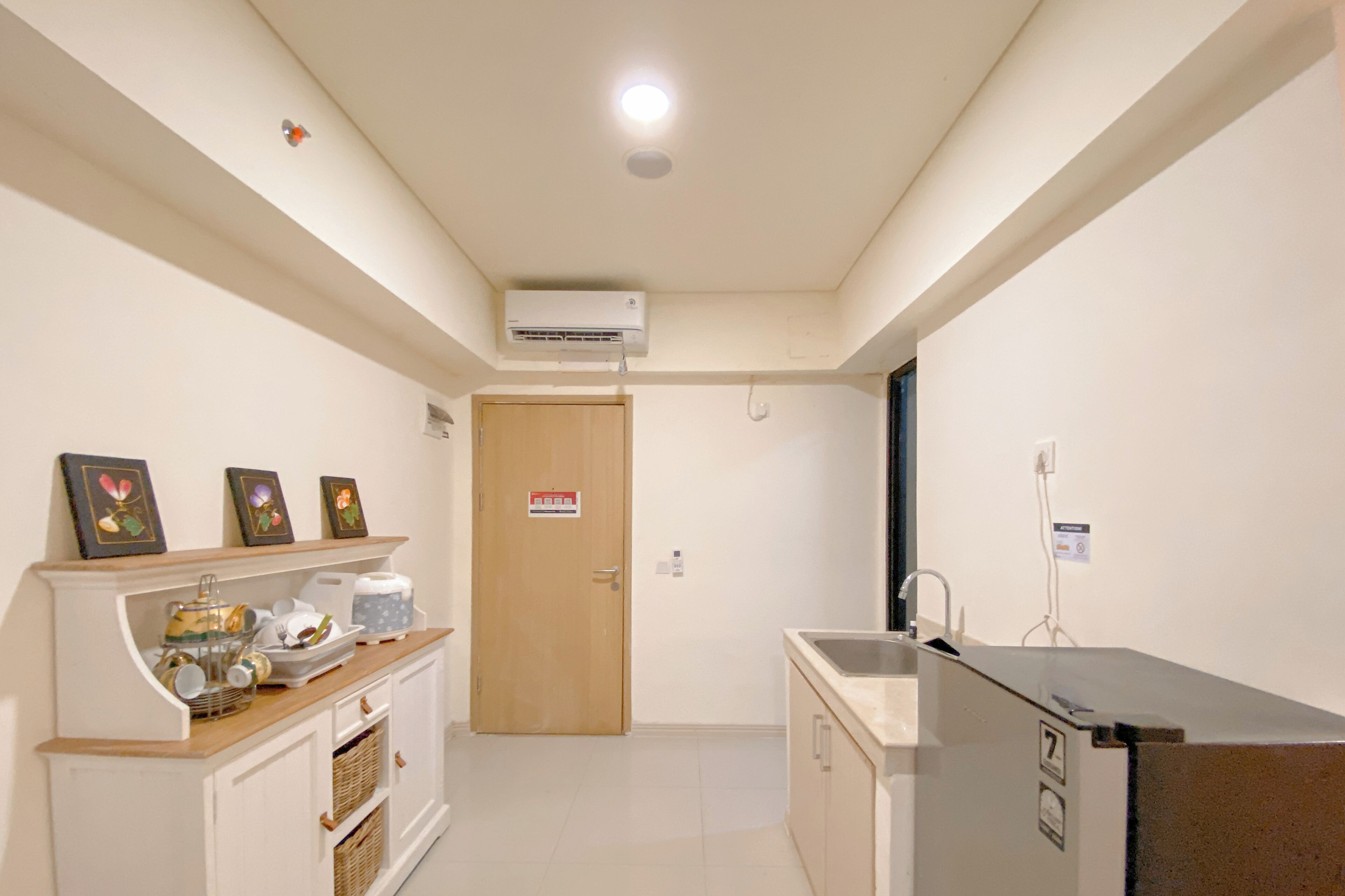 Une cuisine compacte avec un meuble en bois, un évier et un appareil de climatisation fixé au mur.
