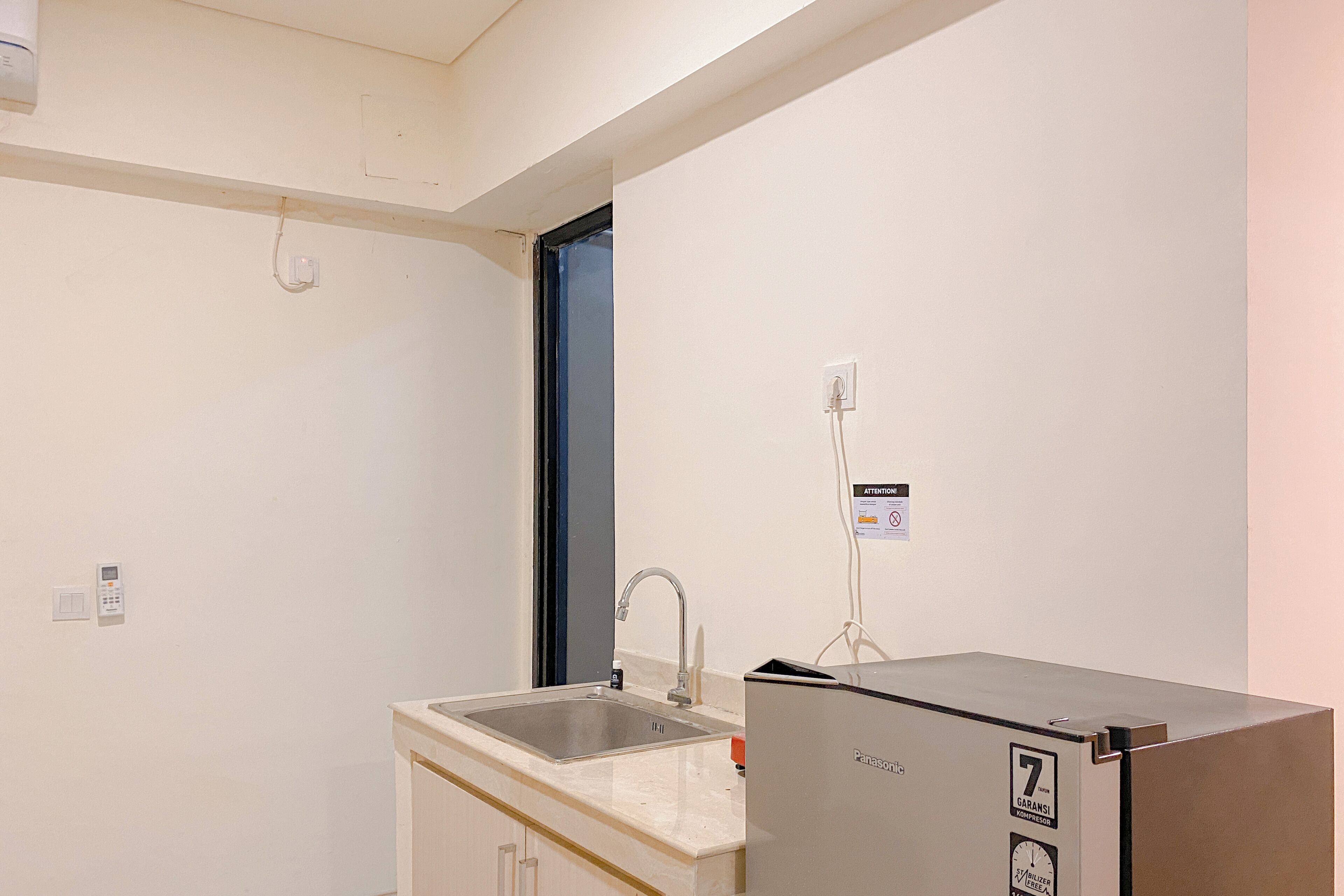 A small kitchenette with a sink, a countertop, and a refrigerator.