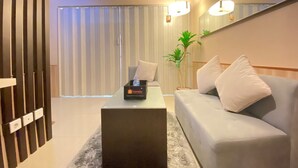 A modern living room with a sofa, a coffee table, and a travel-themed box. - Cozy and Stylish 1BR Apartment at Gateway Pasteur (Cimahi)