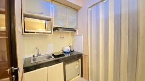 A compact kitchen with a microwave, sink, and a small countertop. - Cozy and Stylish 1BR Apartment at Gateway Pasteur (Cimahi)