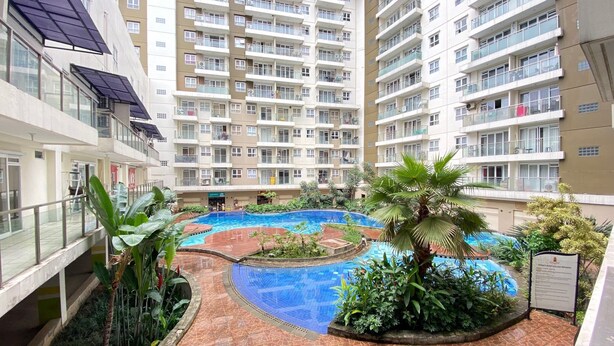 A multi-story residential building with a central swimming pool surrounded by greenery. - Cozy and Stylish 1BR Apartment at Gateway Pasteur (Cimahi)