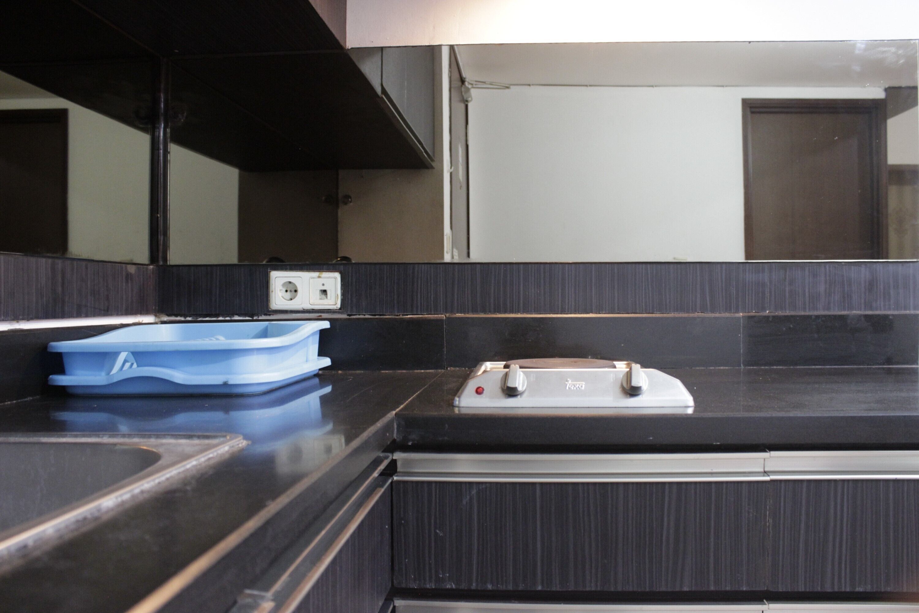 A kitchen with a black countertop, a blue dish rack, and a stove.