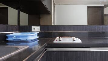 A kitchen with a black countertop, a blue dish rack, and a stove.