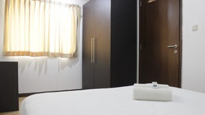 A hotel room with a bed, a wardrobe, and a window with curtains. - Deluxe & Comfy 2BR at Braga City Walk Apartment (Bandung)