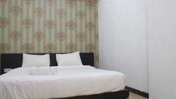 A neatly made bed with white linens and two pillows, a dark headboard, and a patterned curtain in the background.