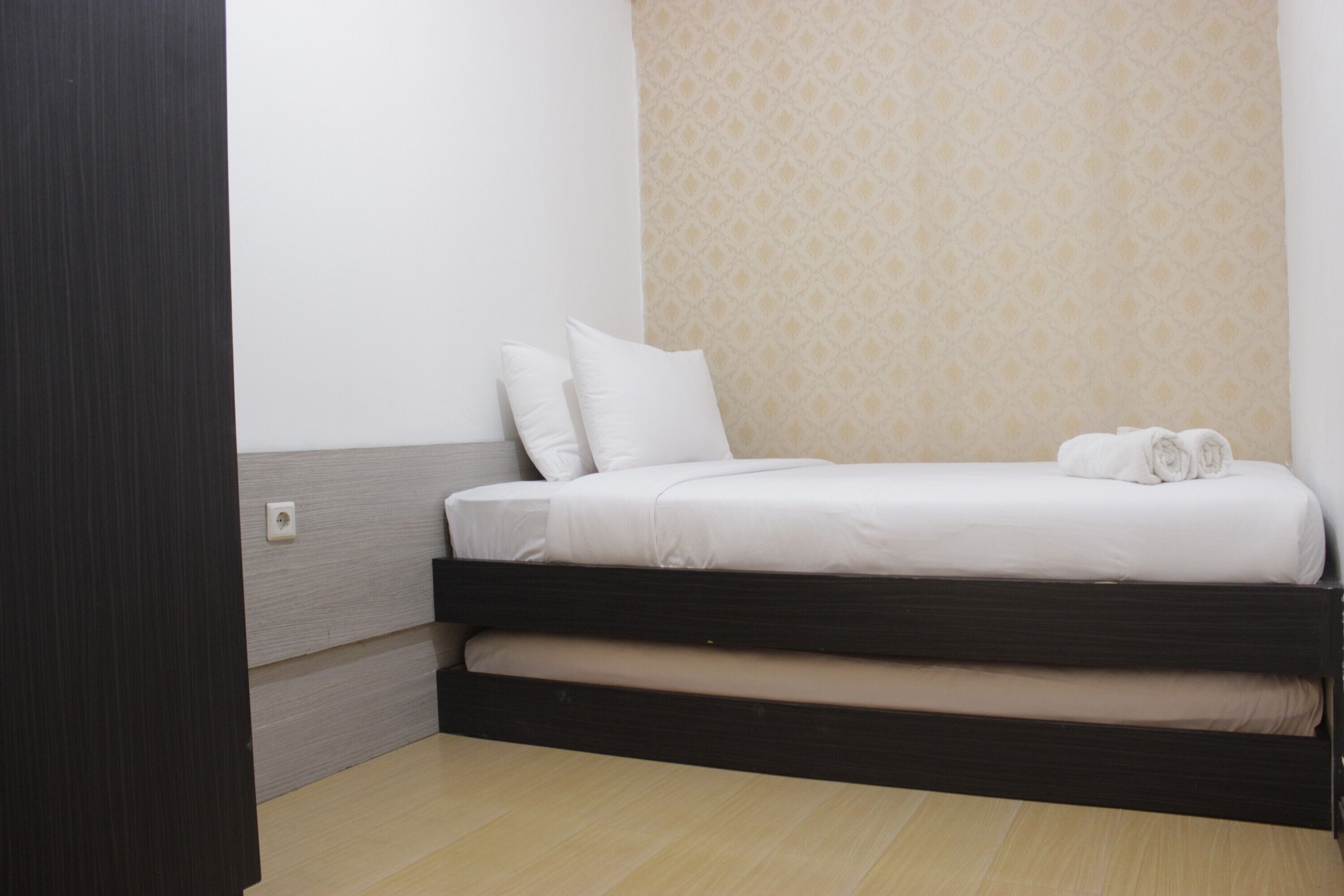 A minimalist room with a bed, a wooden floor, and a patterned wall.