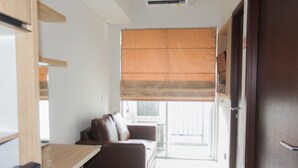 Una habitación compacta con un sofá marrón, una mesita y una puerta que da a un balcón.