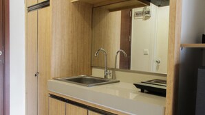 Una cocina con gabinetes de madera, un lavamanos de acero inoxidable y un microondas.