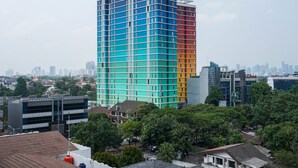A multi-story building with a grid-like facade, surrounded by trees and other buildings. - New Furnish and Homey 1BR Apartment at Pejaten Park Residence (Jakarta)