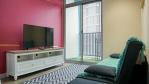 A bedroom with a TV on a white dresser, a bed with a green blanket, and a sliding glass door to a balcony. - New Furnish and Homey 1BR Apartment at Pejaten Park Residence (Jakarta)