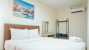 A hotel room with a bed, a painting of a bridge, a mirror, a towel rack, and an air conditioner. - New Furnish and Homey 1BR Apartment at Pejaten Park Residence (Jakarta)