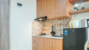 A kitchen with wooden cabinets, a stainless steel refrigerator, and a tiled backsplash. - New Furnish and Homey 1BR Apartment at Pejaten Park Residence (Jakarta)